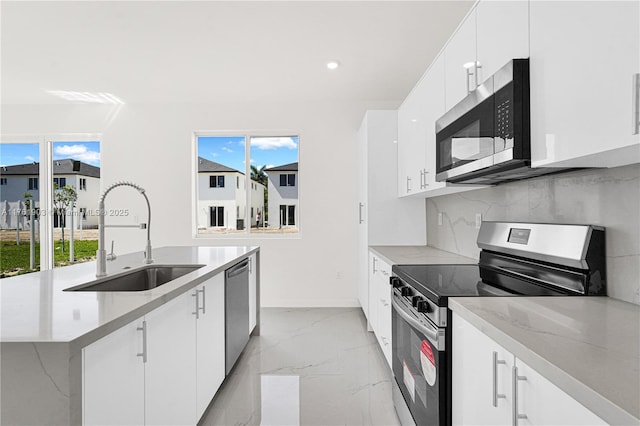 kitchen with marble finish floor, a center island with sink, a sink, appliances with stainless steel finishes, and decorative backsplash