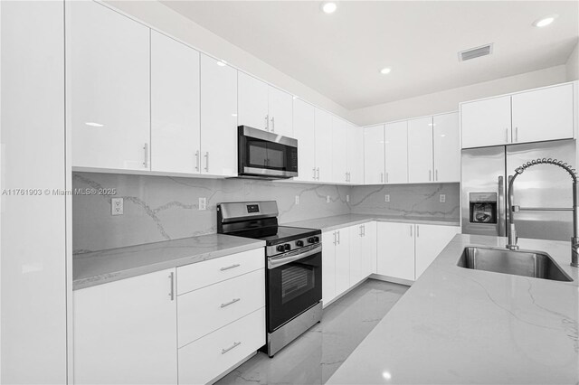 kitchen featuring light stone countertops, visible vents, a sink, appliances with stainless steel finishes, and marble finish floor