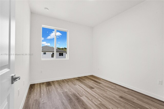 unfurnished room featuring baseboards and wood finished floors