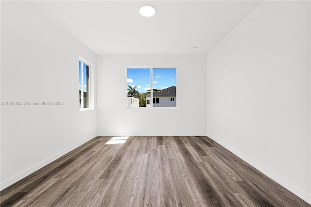 spare room featuring baseboards and wood finished floors