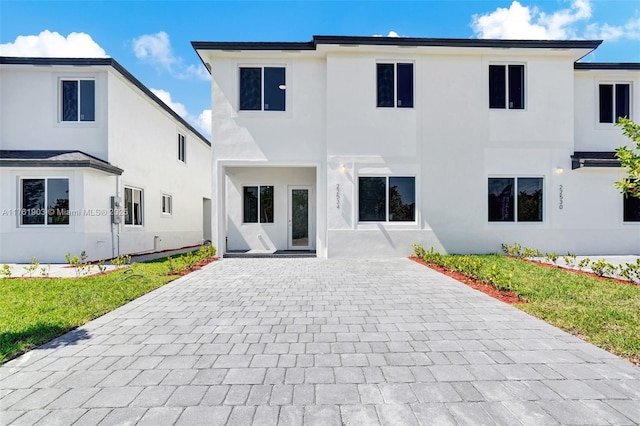 rear view of house with a patio area, a lawn, and stucco siding