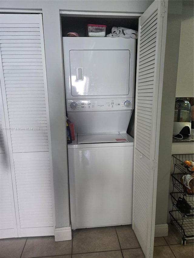 laundry room featuring tile patterned flooring, laundry area, and stacked washer and clothes dryer