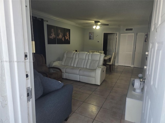 living area with visible vents, a ceiling fan, a textured ceiling, crown molding, and tile patterned flooring