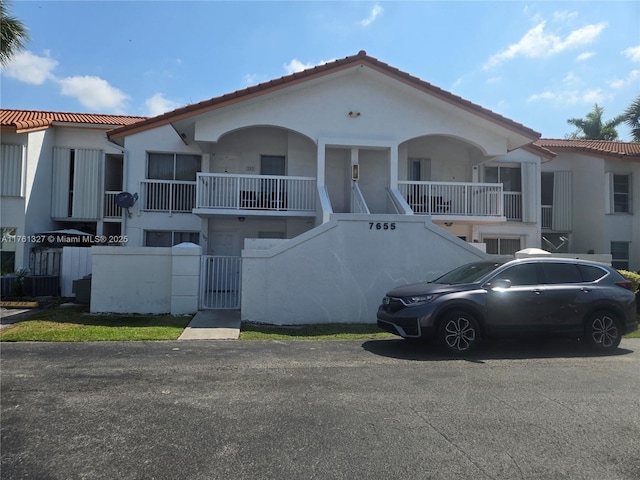 view of front of property with stairway, stucco siding, and fence