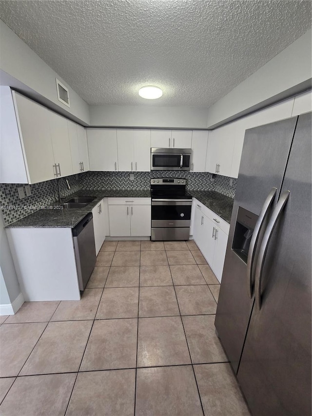 7655 SW 153rd Ct Unit 102, Miami, FL 33193 - kitchen featuring appliances with stainless steel finishes, a sink, tasteful backsplash, white cabinets, and a textured ceiling