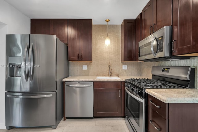 kitchen featuring a sink, decorative backsplash, light countertops, dark brown cabinetry, and appliances with stainless steel finishes