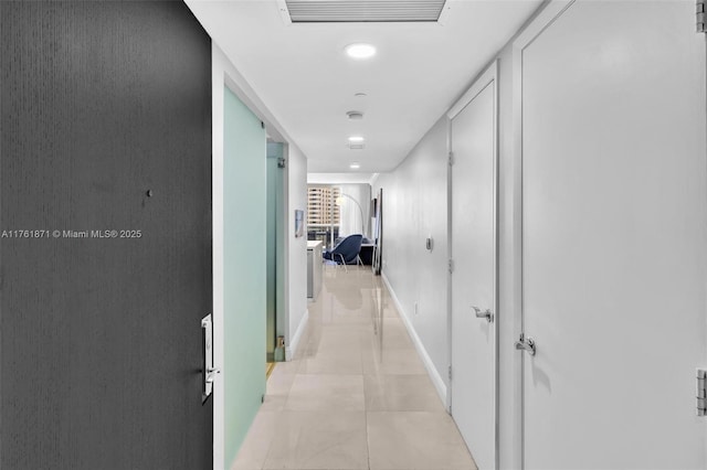 corridor featuring light tile patterned floors, visible vents, and baseboards