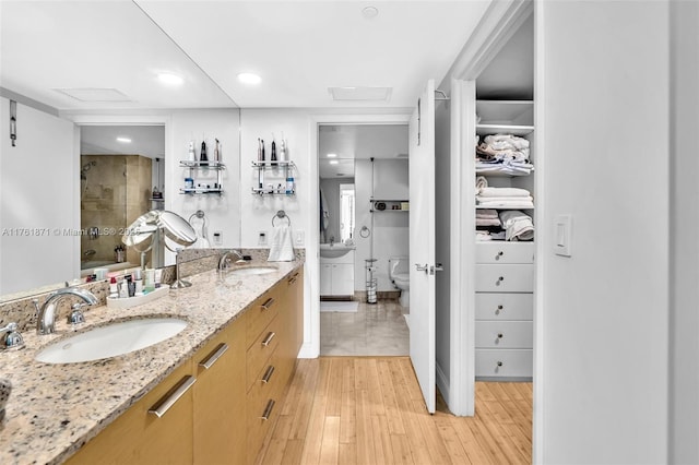 full bathroom featuring double vanity, a shower stall, wood finished floors, and a sink