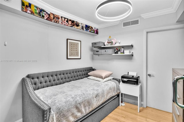 bedroom featuring visible vents, crown molding, and wood finished floors