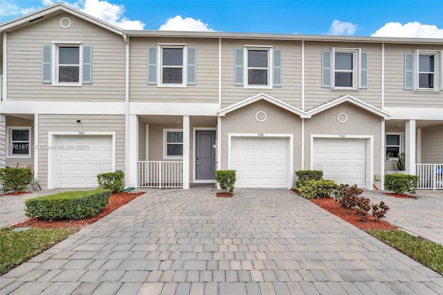 townhome / multi-family property featuring decorative driveway and a garage