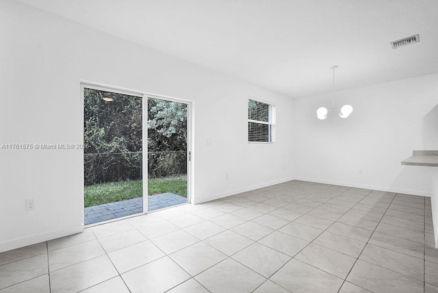 spare room with a wealth of natural light, visible vents, baseboards, and a chandelier