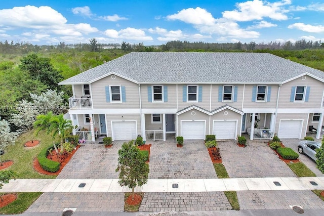 townhome / multi-family property featuring a porch, a garage, driveway, and a balcony