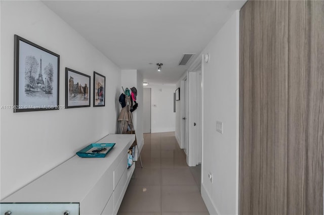 hall featuring light tile patterned floors, baseboards, and visible vents