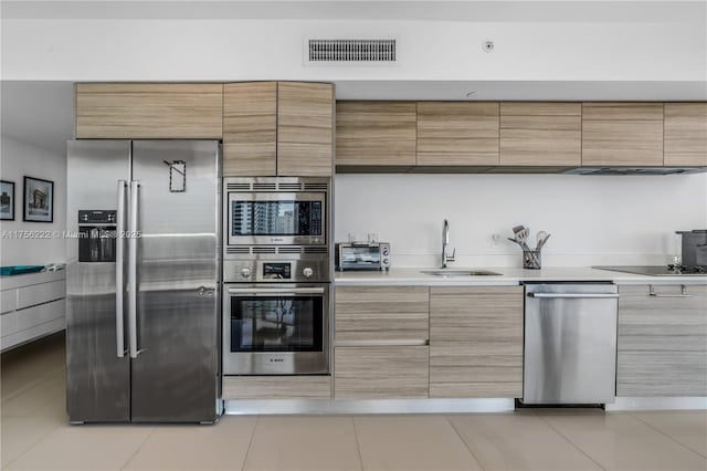 kitchen with modern cabinets, stainless steel appliances, light countertops, and a sink