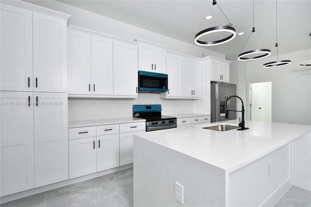 kitchen with a kitchen island with sink, a sink, decorative light fixtures, stainless steel appliances, and white cabinets