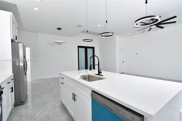 kitchen featuring an island with sink, a sink, freestanding refrigerator, dishwashing machine, and hanging light fixtures