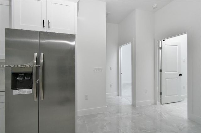 kitchen featuring white cabinetry, baseboards, stainless steel fridge, and marble finish floor