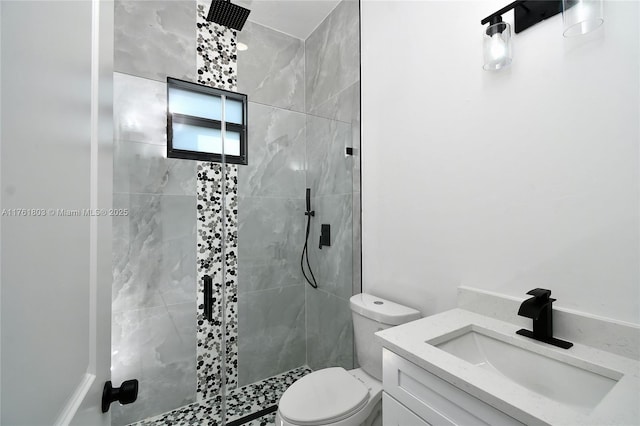 bathroom featuring toilet, tiled shower, and vanity