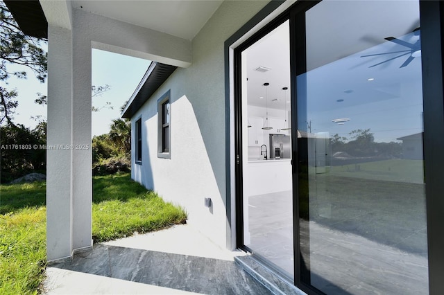 doorway to outside featuring ceiling fan, a textured wall, visible vents, and a sink