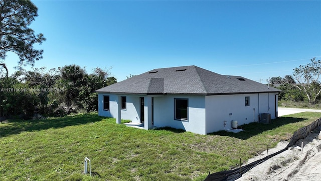 back of property with cooling unit, a yard, roof with shingles, and stucco siding