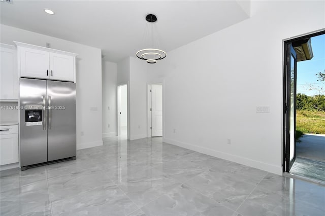 kitchen with baseboards, stainless steel fridge with ice dispenser, light countertops, pendant lighting, and white cabinetry