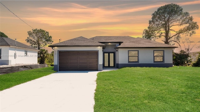 view of front of property featuring a garage, a lawn, driveway, and stucco siding