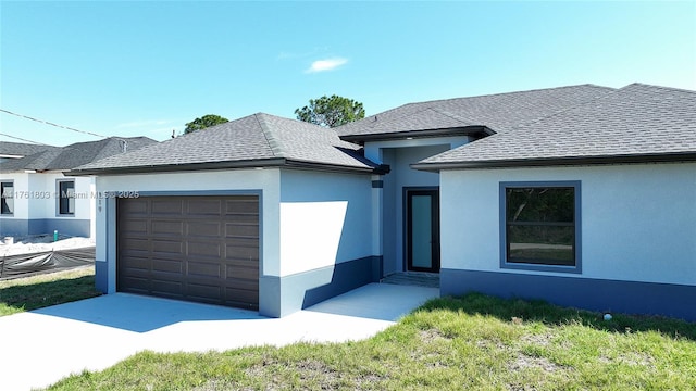 view of front of home with stucco siding, an attached garage, and a shingled roof