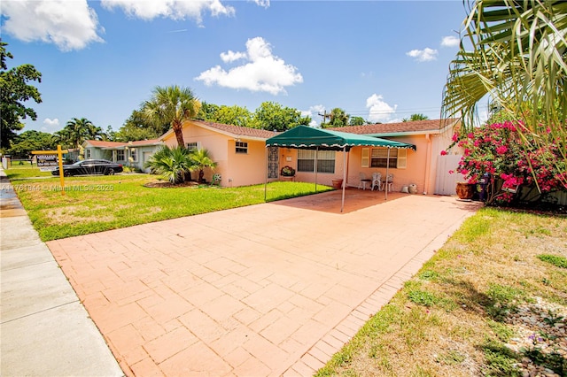 ranch-style home featuring a patio area, stucco siding, driveway, and a front lawn