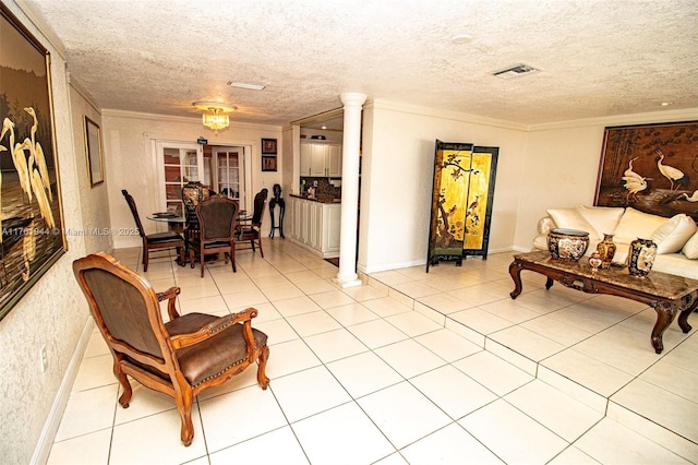 living area featuring tile patterned flooring, a textured ceiling, crown molding, and decorative columns