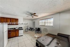 living area with a textured ceiling, light tile patterned flooring, and ceiling fan