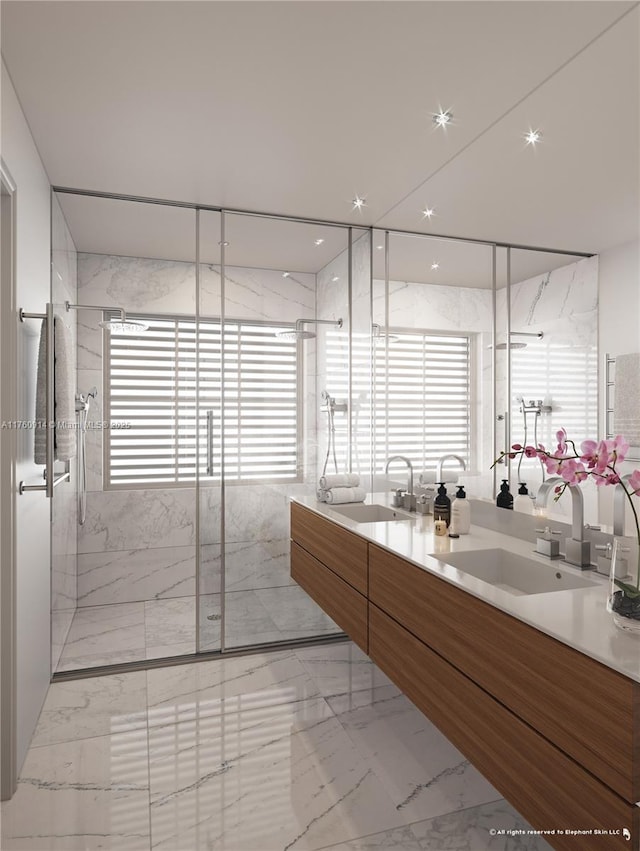 full bath featuring a marble finish shower, marble finish floor, double vanity, and a sink