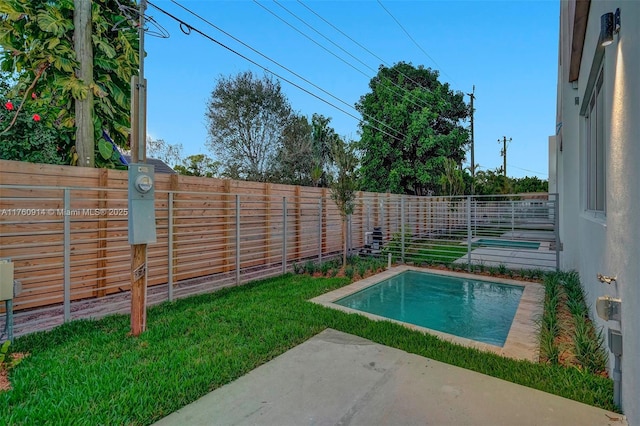 view of swimming pool featuring a fenced backyard, a yard, and a patio area
