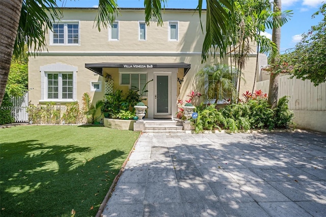 view of front of property featuring stucco siding, a front yard, and fence