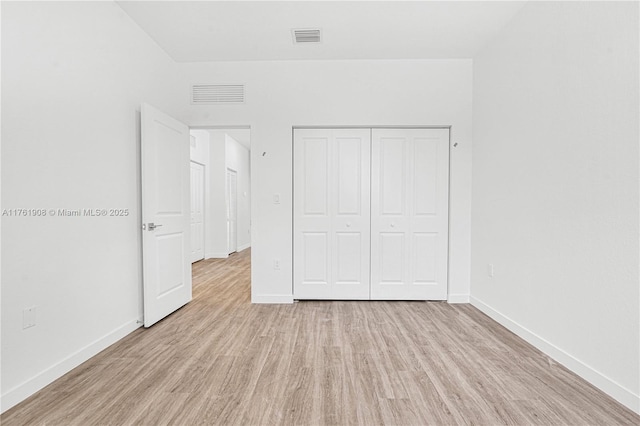 unfurnished bedroom featuring visible vents, baseboards, light wood-style floors, and a closet