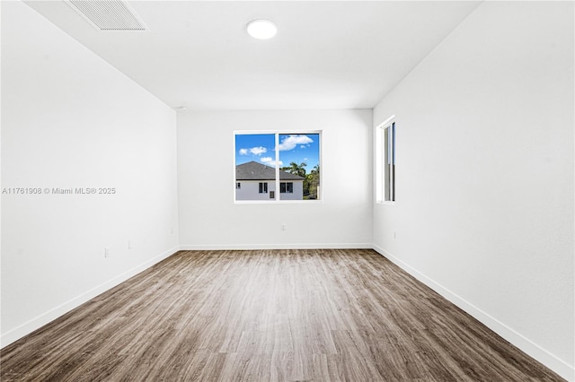 spare room featuring wood finished floors, visible vents, and baseboards