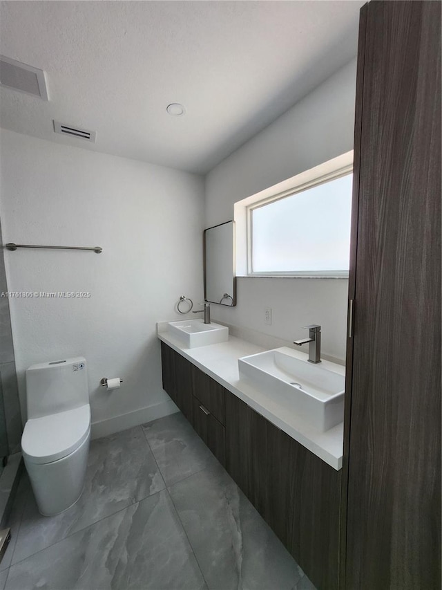 bathroom featuring a sink, visible vents, toilet, and marble finish floor