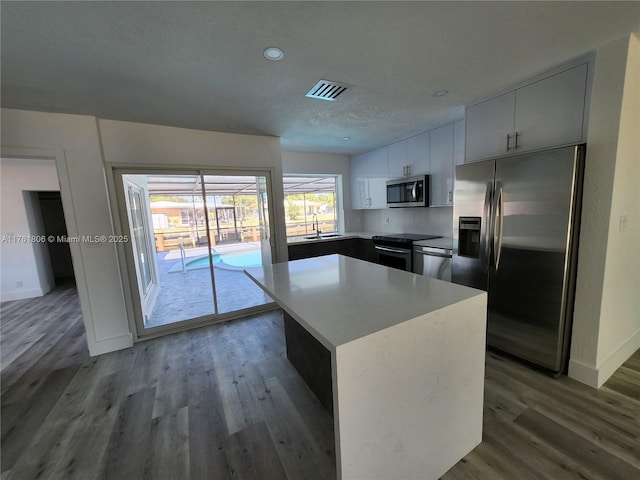 kitchen featuring wood finished floors, visible vents, light countertops, appliances with stainless steel finishes, and a center island