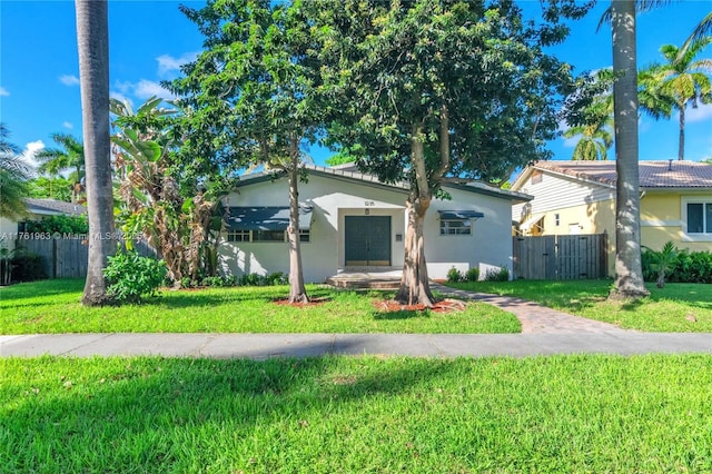 view of front facade with a front yard, fence, and stucco siding