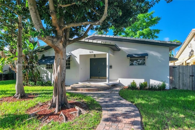 bungalow with stucco siding, a front yard, and fence