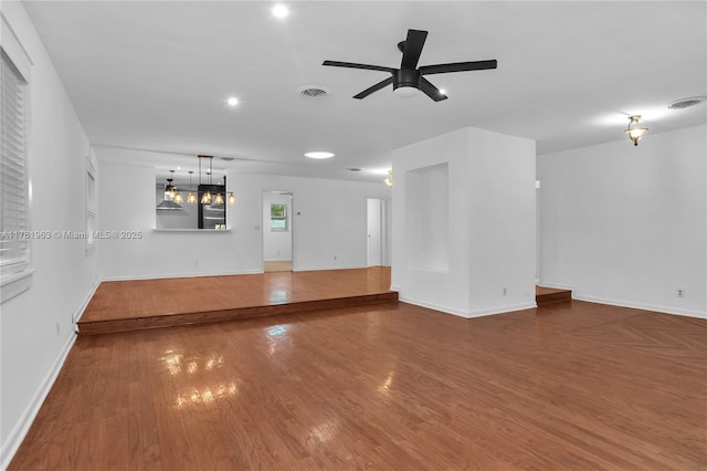 unfurnished living room featuring baseboards, wood finished floors, visible vents, and ceiling fan