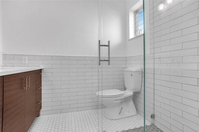 full bathroom featuring toilet, a stall shower, tile walls, wainscoting, and tile patterned flooring