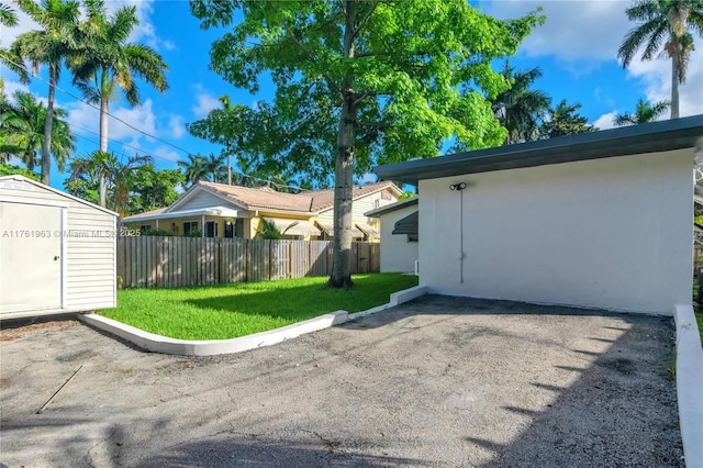 view of yard featuring a storage unit, a patio, an outdoor structure, and fence