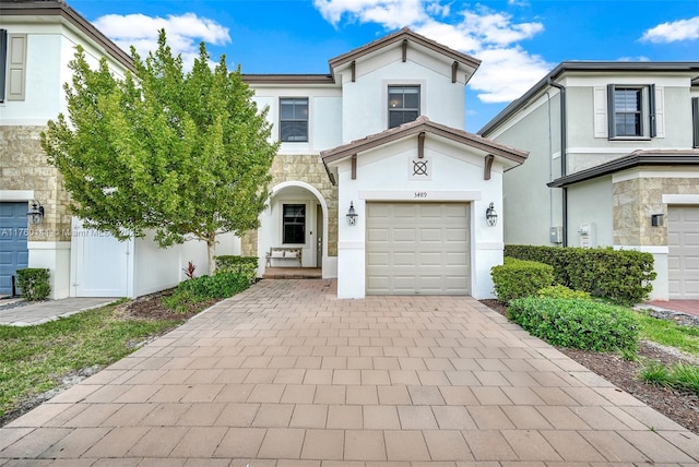 view of front of home featuring stone siding, stucco siding, and decorative driveway