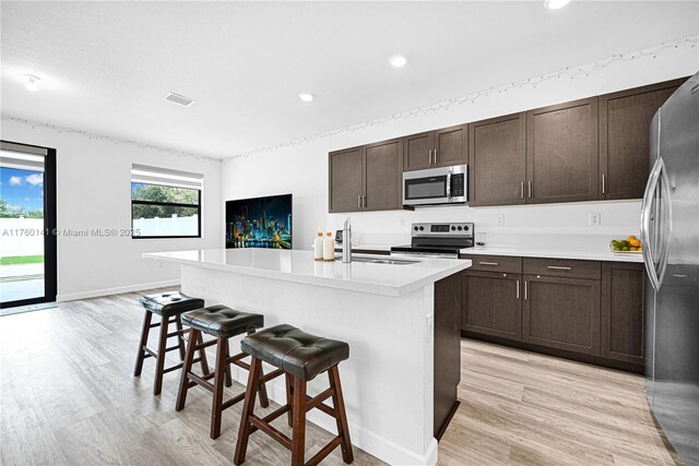 3489 W 110th Ter, Hialeah, FL 33018 - kitchen with light countertops, dark brown cabinets, light wood finished floors, and stainless steel fridge with ice dispenser