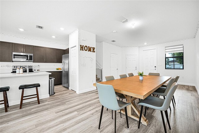 3489 W 110th Ter, Hialeah, FL 33018 - kitchen with a sink, light wood finished floors, a breakfast bar, and stainless steel appliances
