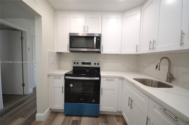 kitchen with wood finished floors, electric range, a sink, white cabinets, and stainless steel microwave