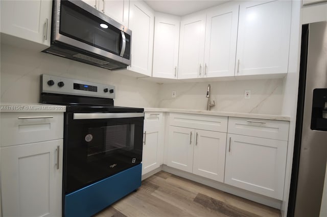 kitchen featuring light wood-style floors, appliances with stainless steel finishes, white cabinets, and light countertops