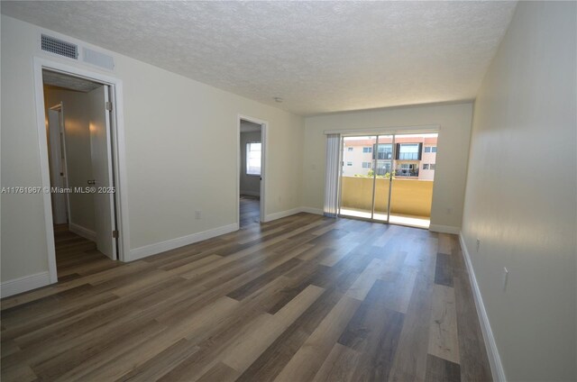 6070 W 18th Ave Unit 310, Hialeah, FL 33012 - spare room with a textured ceiling, dark wood-style flooring, and baseboards
