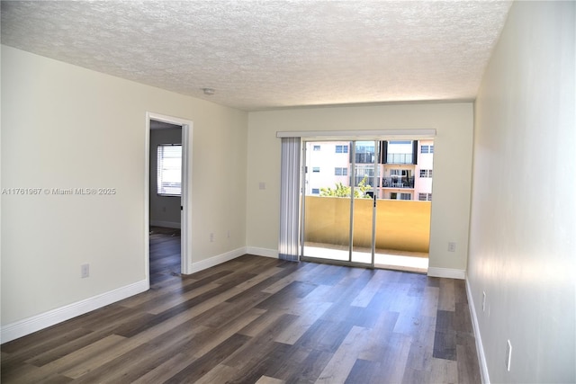 unfurnished room featuring dark wood-style floors, a textured ceiling, and baseboards