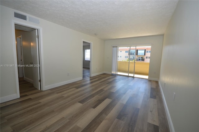 spare room with visible vents, a textured ceiling, and wood finished floors